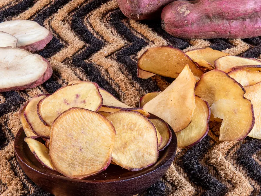 Purple-skinned sweet potatoes and Frittas sweet potato chips in a wooden bowl
