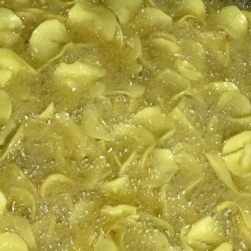 Cassava chips frying in hot oil, surrounded by bubbles