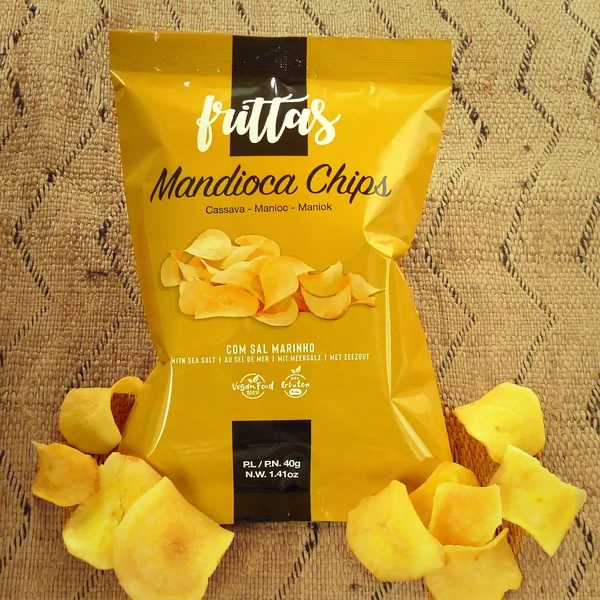 Bag of Frittas cassava chips surrounded by loose chips, on a woven mat